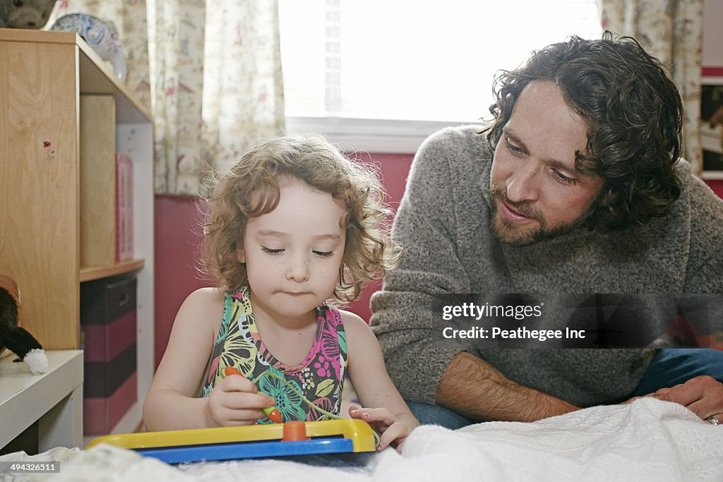 Caucasian father and daughter playing in bedroom