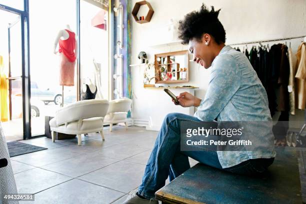 mixed race woman using cell phone in store - a la moda stock pictures, royalty-free photos & images