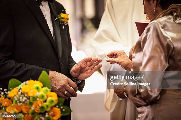 senior couple exchanging rings at wedding - promesas de matrimonio fotografías e imágenes de stock