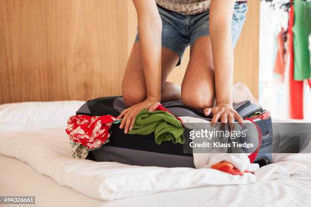 woman packing suitcase on bed - suitcase packing stockfoto's en -beelden