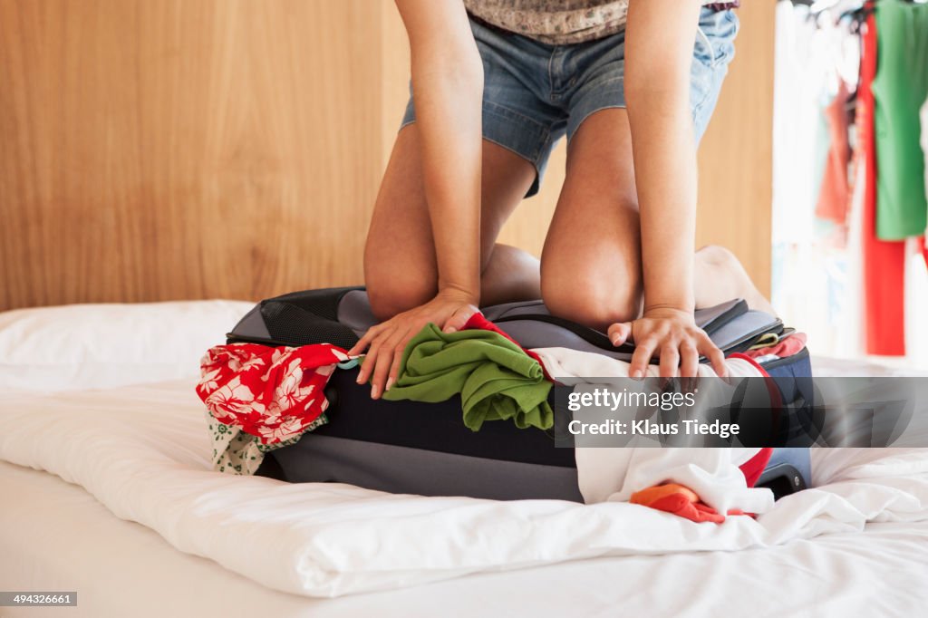Woman packing suitcase on bed