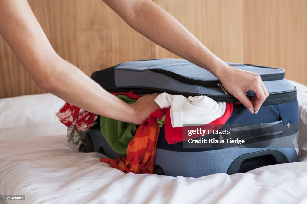 Woman packing suitcase on bed