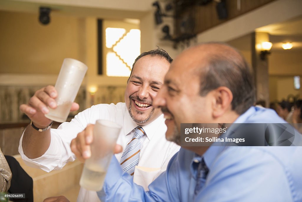 Hispanic men drinking at wedding reception