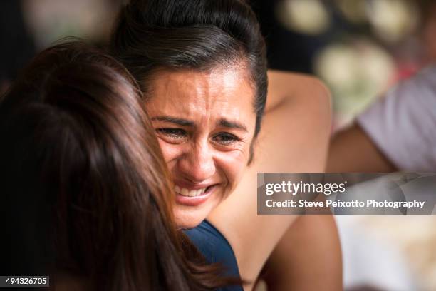 hispanic women hugging and crying - emociones fotografías e imágenes de stock
