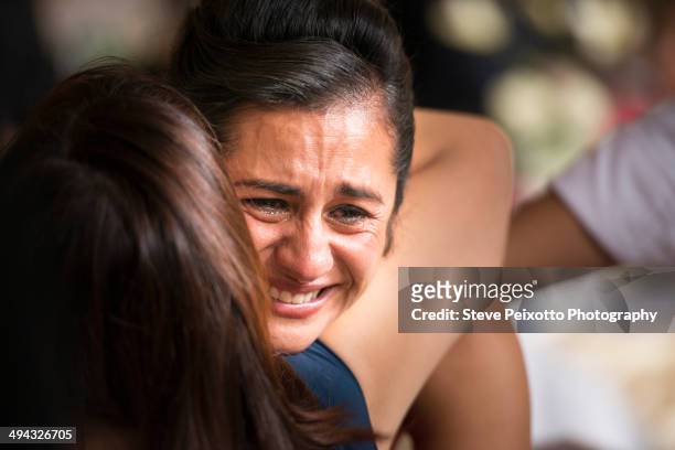 hispanic women hugging and crying - abbracciare una persona foto e immagini stock