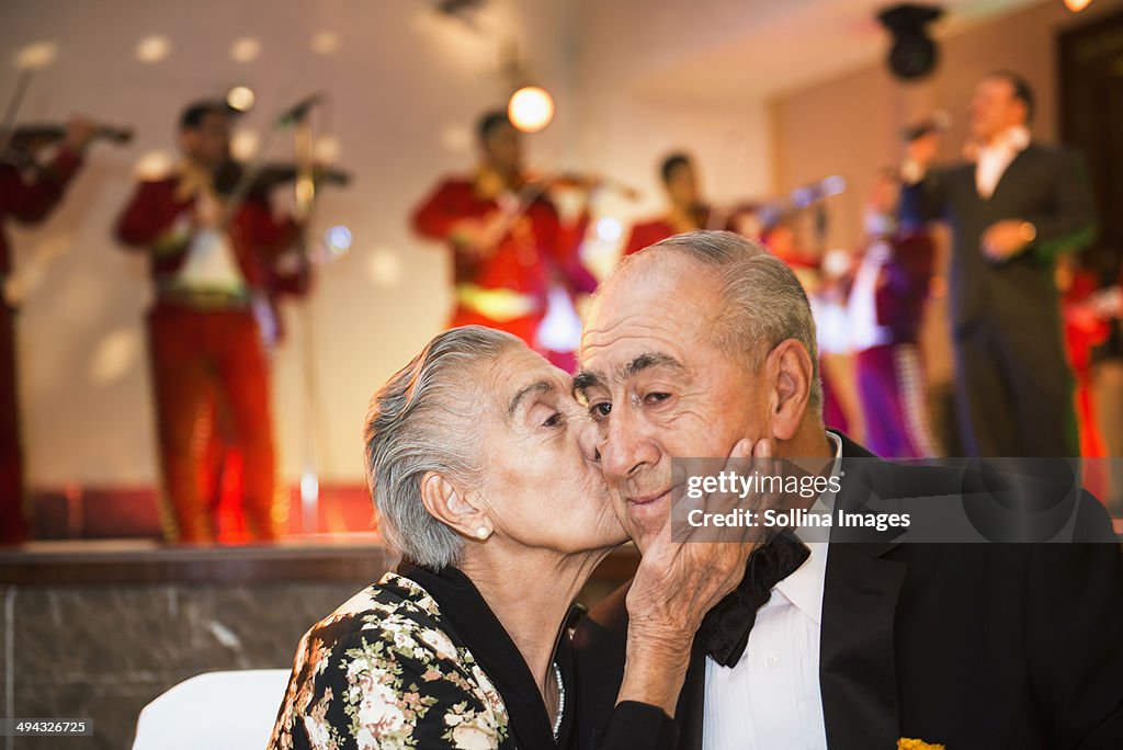 Hispanic couple kissing at wedding reception