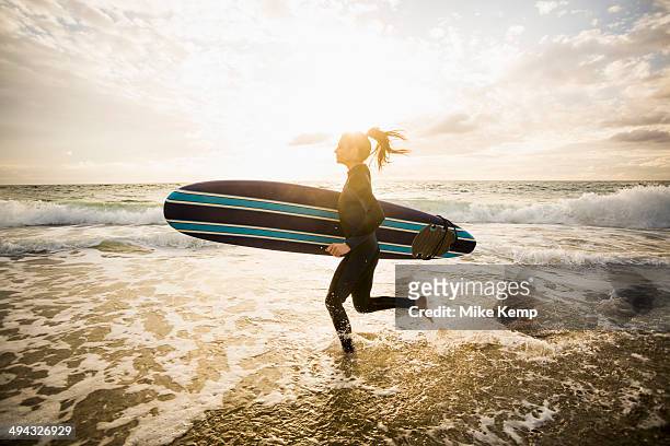caucasian surfer carrying board in waves - ボード　持つ　女性 ストックフォトと画像