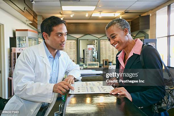 optometrist talking to patient in office - eye doctor and patient stock pictures, royalty-free photos & images