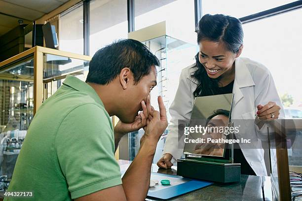 optometrist helping patient with contacts in office - lente de contacto imagens e fotografias de stock