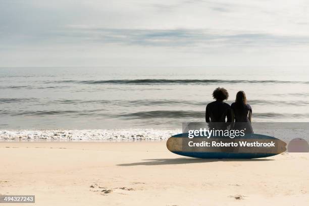 surfers sitting on board on beach - sitting on surfboard ストックフォトと画像