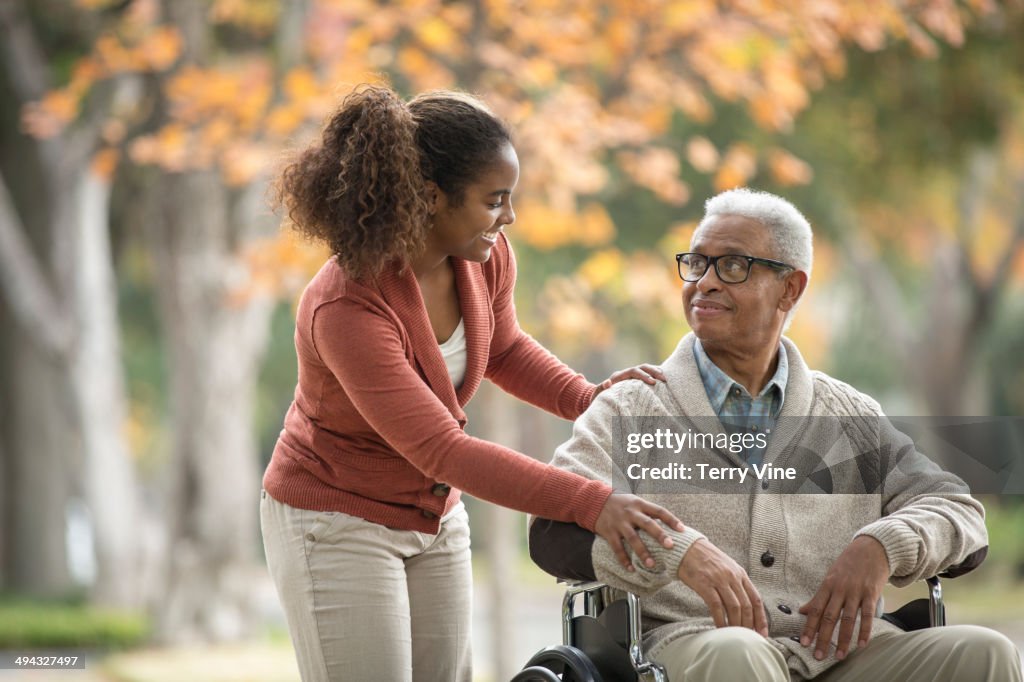 African American woman pushing father in wheelchair