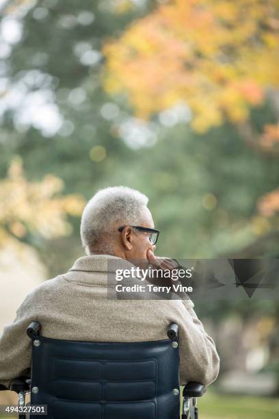 african american man sitting in wheelchair outdoors - african american man day dreaming stock pictures, royalty-free photos & images