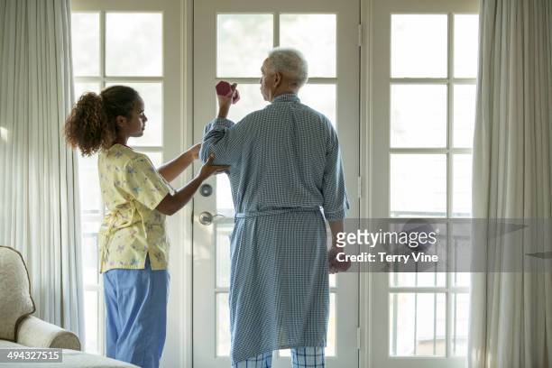 african american nurse helping patient with physical therapy - ergotherapie stock-fotos und bilder