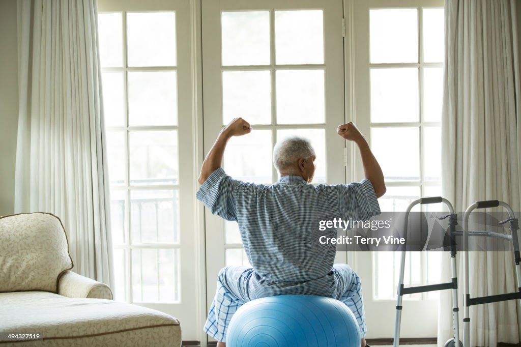 Senior African American man on fitness ball at home