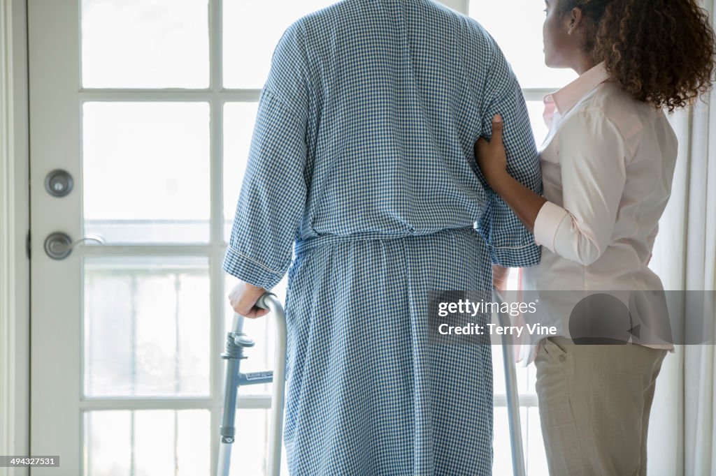 African American woman helping Senior man use walker