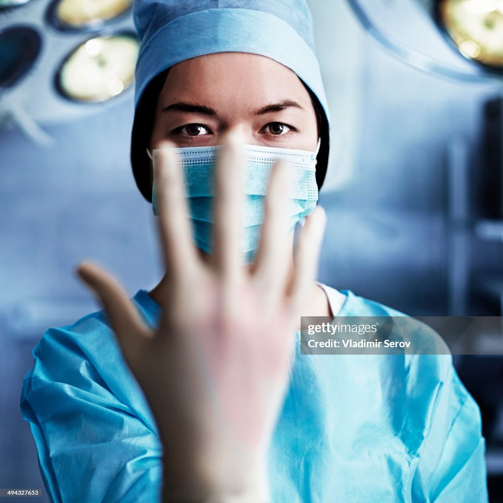 Caucasian surgeon pulling on glove in operating room
