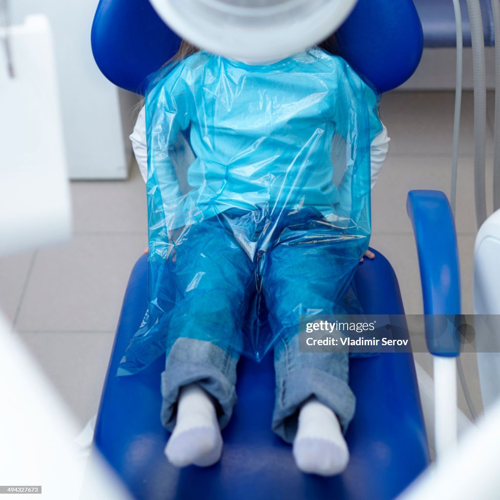 Caucasian girl wearing plastic sheet at dentist