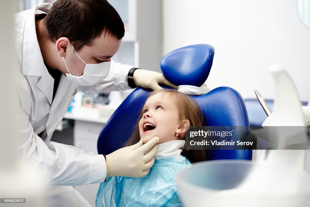 Caucasian dentist examining girl's teeth