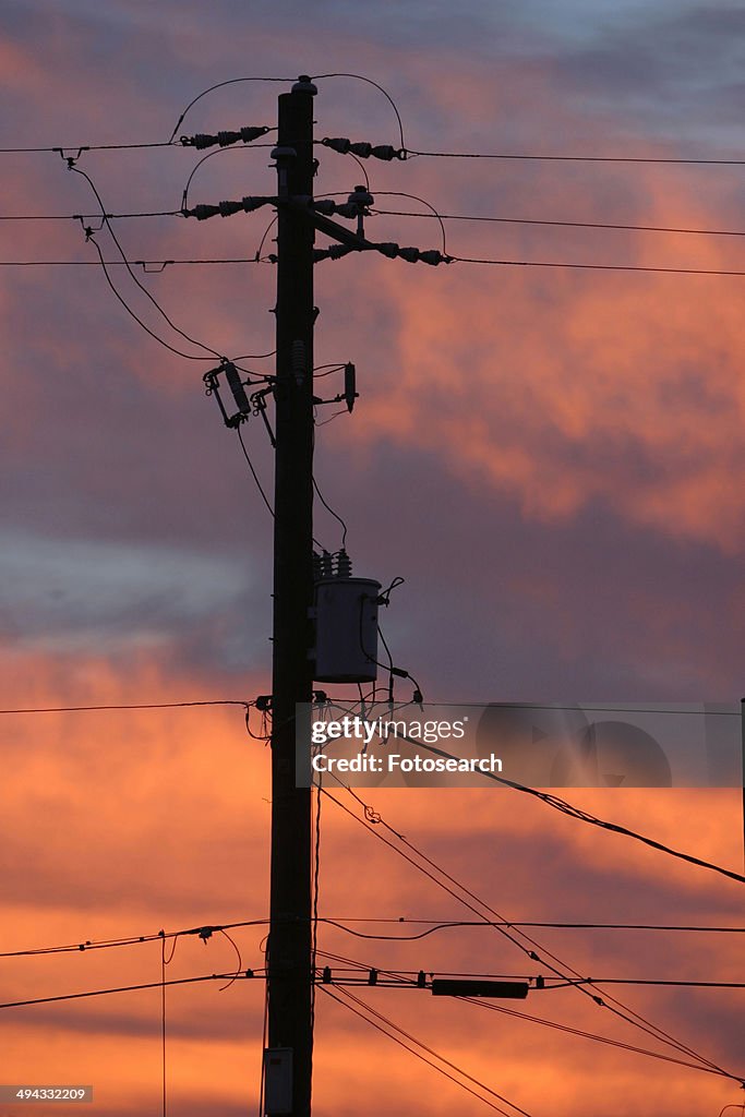 Electric pole in silhouette against colorful sky