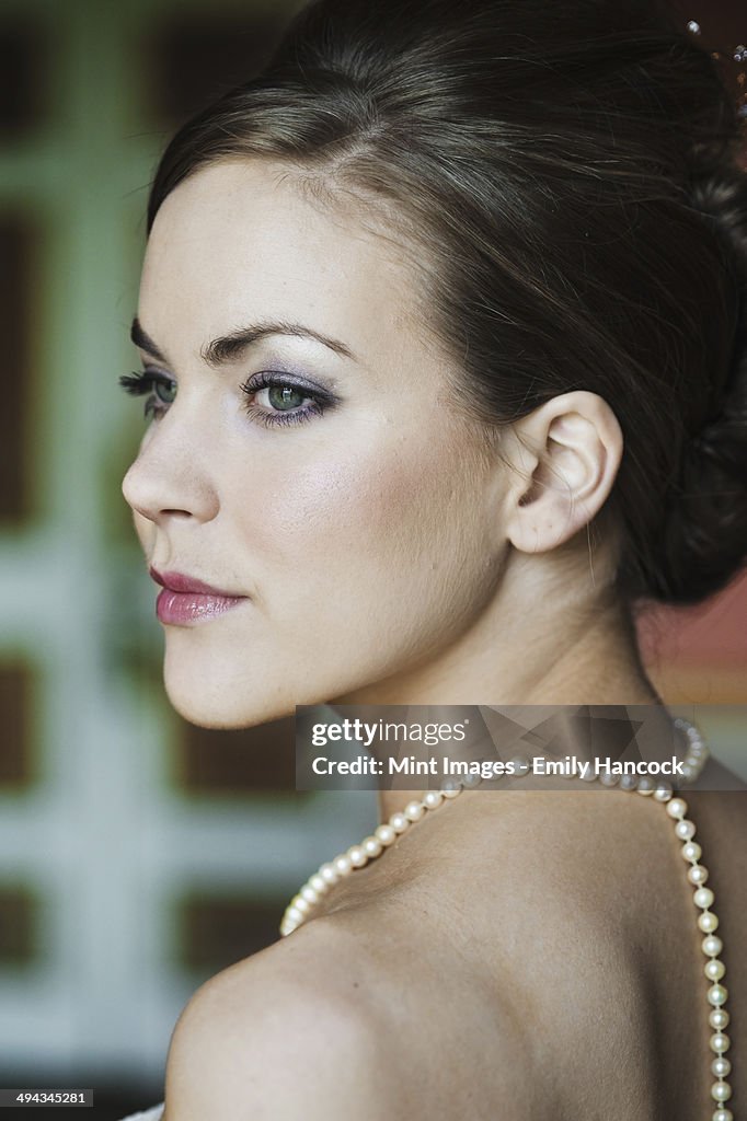 A woman with brown hair, wearing a pearl necklace.