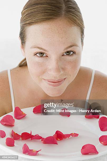 a spa treatment centre. a young woman with a white dish of pink rose petals. - white rose flower spa stock-fotos und bilder