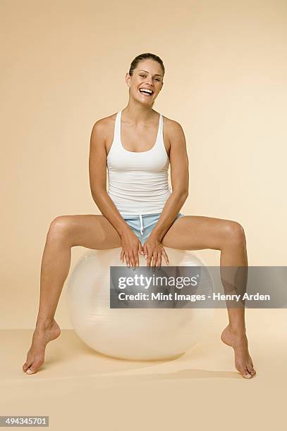 a woman in vest and shorts sitting on an exercise ball. - legs apart stock pictures, royalty-free photos & images