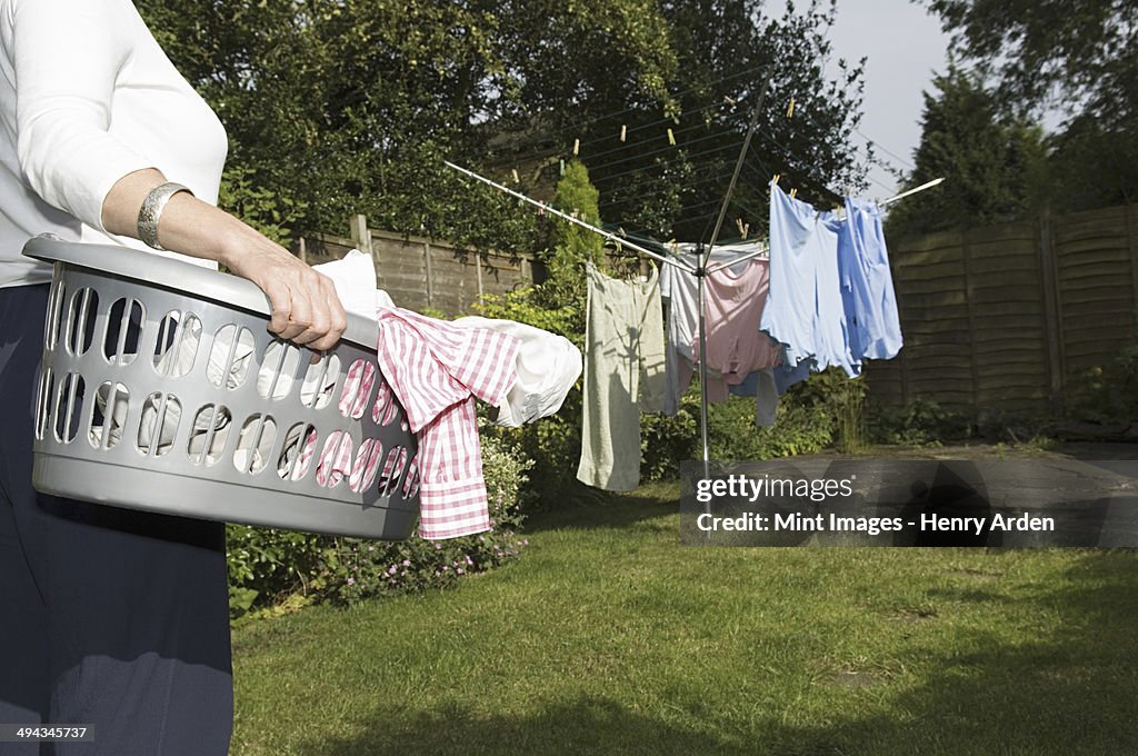 A woman carrying a basket of washing out to the washing line.
