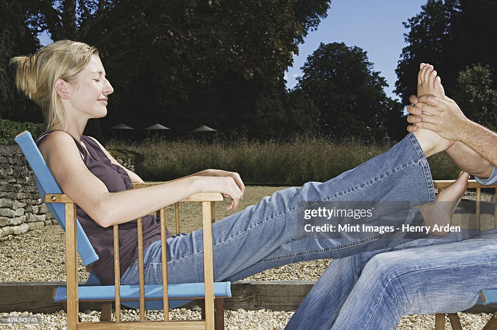 A woman seated with her legs outstretched, having a foot massage.