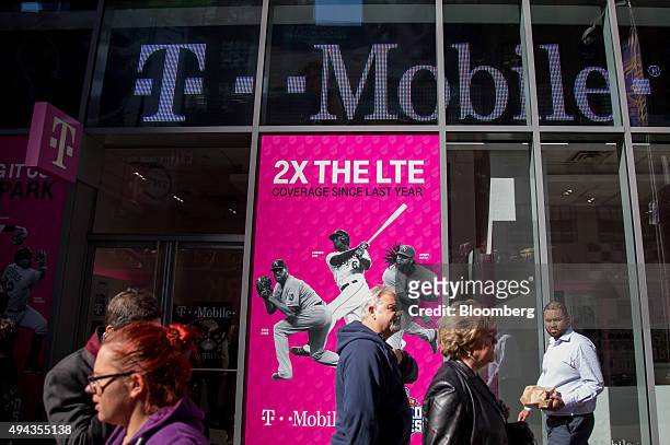 Pedestrians walk past a T-Mobile US Inc. Store in New York, U.S., on Monday, Oct. 26, 2015. T-Mobile US Inc. Is scheduled to release earnings figures...
