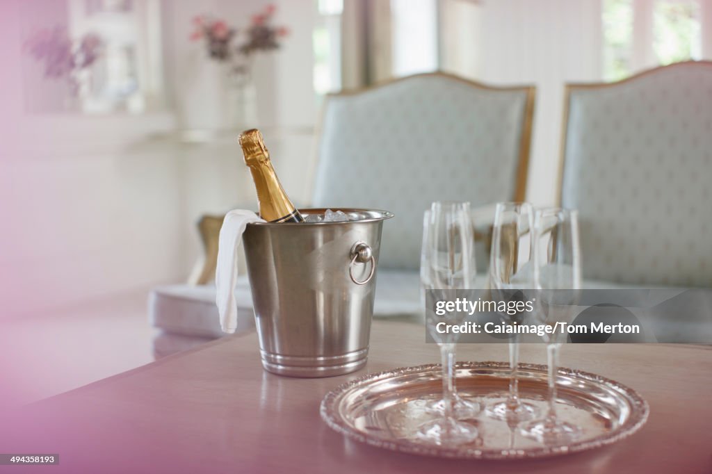 Champagne in silver bucket next to champagne flutes