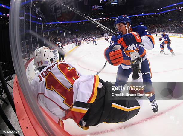 Travis Hamonic of the New York Islanders checks Josh Jooris of the Calgary Flames into the boards during the first period at the Barclays Center on...
