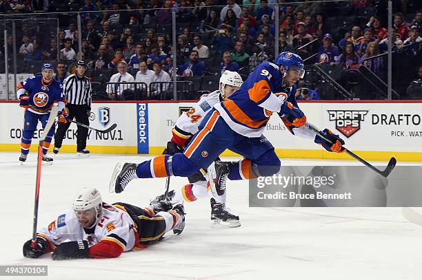 John Tavares of the New York Islanders gets off a shot while being checked by Mark Giordano and Jiri Hudler of the Calgary Flames during the second...