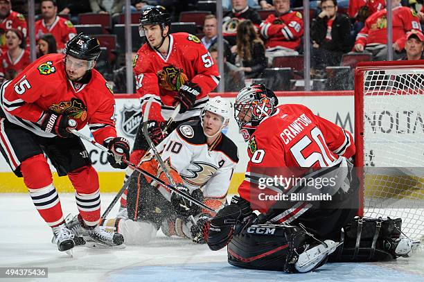 Goalie Corey Crawford and Artem Anisimov of the Chicago Blackhawks wait for the puck, as Corey Perry of the Anaheim Ducks and Trevor van Riemsdyk...