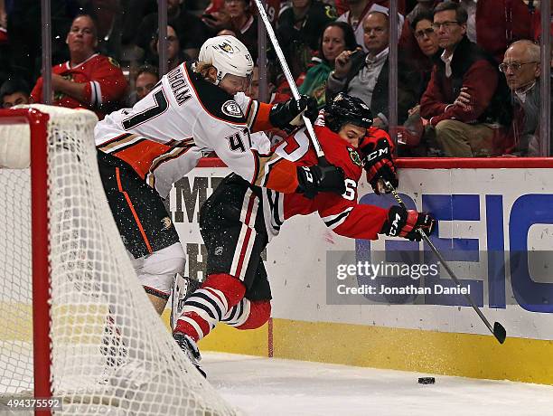 Hampus Lindholm of the Anaheim Ducks checks Andrew Shaw of the Chicago Blackhawks into the boards behind the goal at the United Center on October 26,...