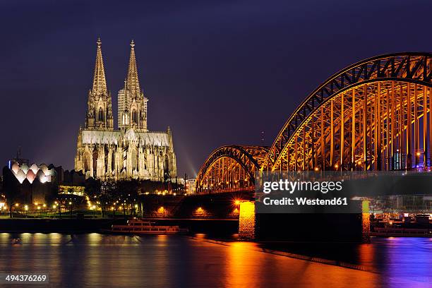 germany, north rhine-westphalia, cologne, view to lighted hohenzollern bridge and cologne cathedral by night - dom van keulen stockfoto's en -beelden