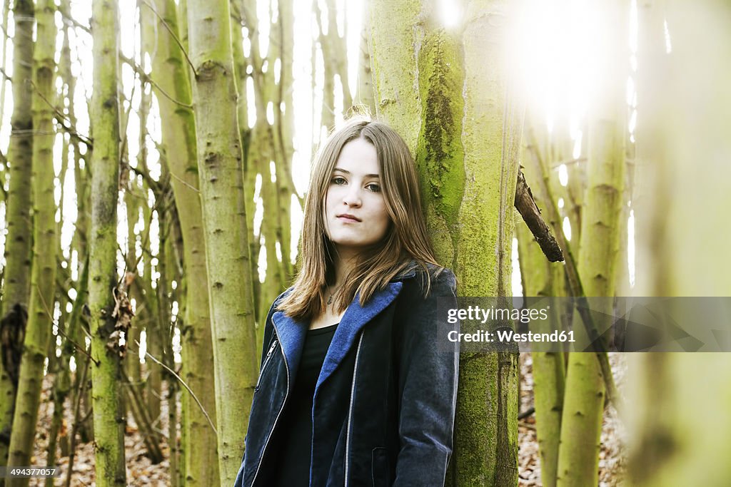 Portrait of teenage girl leaning against tree trunk