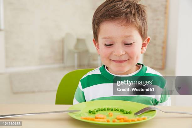 germany, munich , boy eating peas and carrots showing anthropomorphic face - blick nach unten stock-fotos und bilder