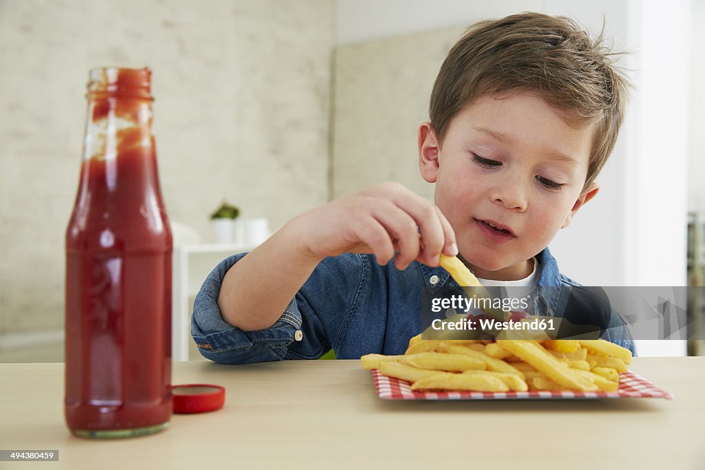 Germany, Munich, Boy eating French fries with ketchup