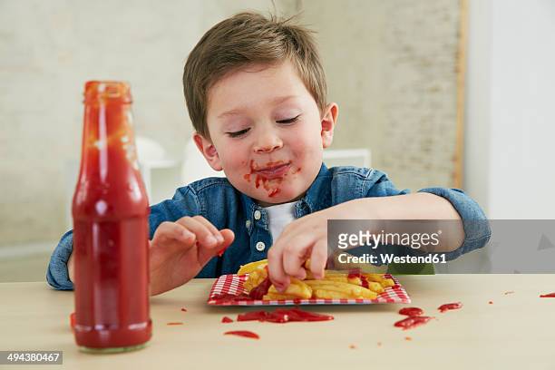 germany, munich, boy eating french fries with ketchup - pikante sauce stock-fotos und bilder