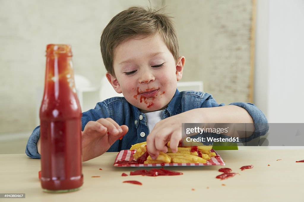 Germany, Munich, Boy eating French fries with ketchup