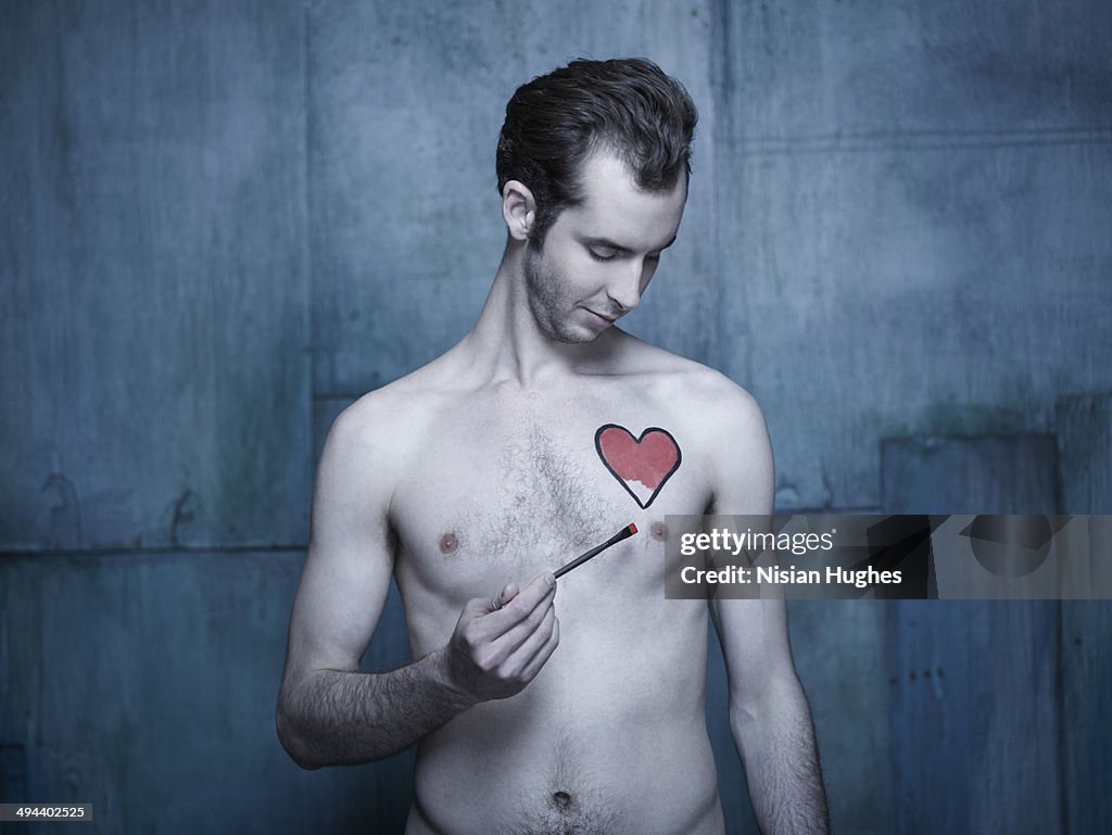 Man painting a heart onto his chest