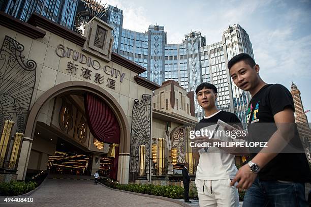 People stand outside the Studio City casino ahead of its opening in Macau on October 27, 2015. Casino operator Melco Crown was to open its latest...
