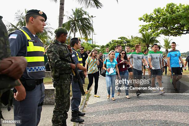 Oliver Bozanic, Tim Cahill and Mark Birighitti walk past police and army personnel during a beach walk at Praca dos Desejos on May 29, 2014 in...