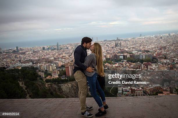 Couple of tourists kiss as they visit a former anti-aircraft bunker with the skyline of Barcelona in the background on October 26, 2015 in Barcelona,...