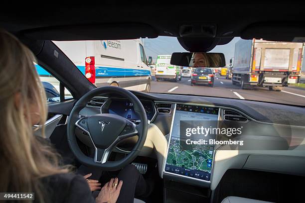 An employee drives a Tesla Motors Inc. Model S electric automobile, equipped with Autopilot hardware and software, hands-free on a highway in...