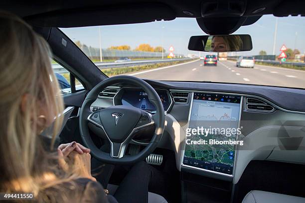 An employee drives a Tesla Motors Inc. Model S electric automobile, equipped with Autopilot hardware and software, hands-free on a highway in...
