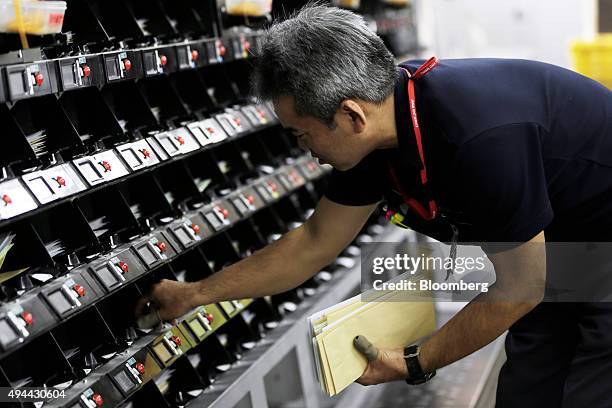 An employee picks up mail from a sorting machine at a Japan Post Co. Post office in Tokyo, Japan, on Monday, Oct. 26, 2015. Japan Post Holdings and...