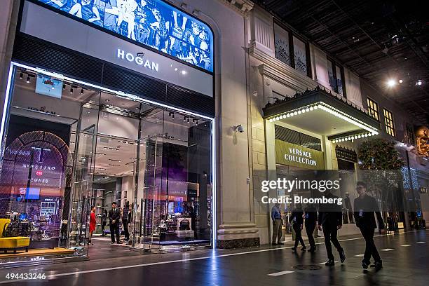 People walk past a Hogan clothing store and a Versace Collection store on The Boulevard at Studio City casino resort, developed by Melco Crown...