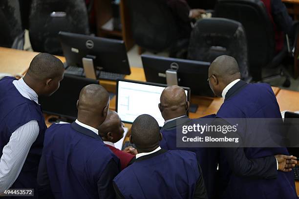 Employees crowd around a computer terminal while working on the trading floor at the Nigerian Stock Exchange in Lagos, Nigeria, on Monday, Oct. 26,...