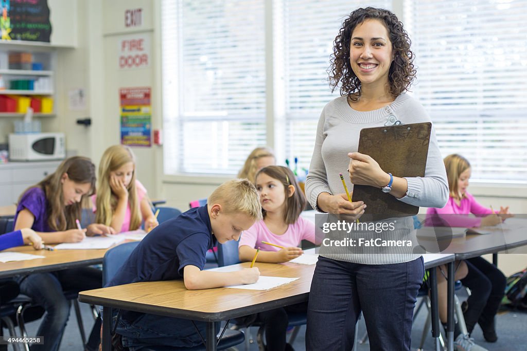 Ethnic female elementary teacher posing in front of classroom